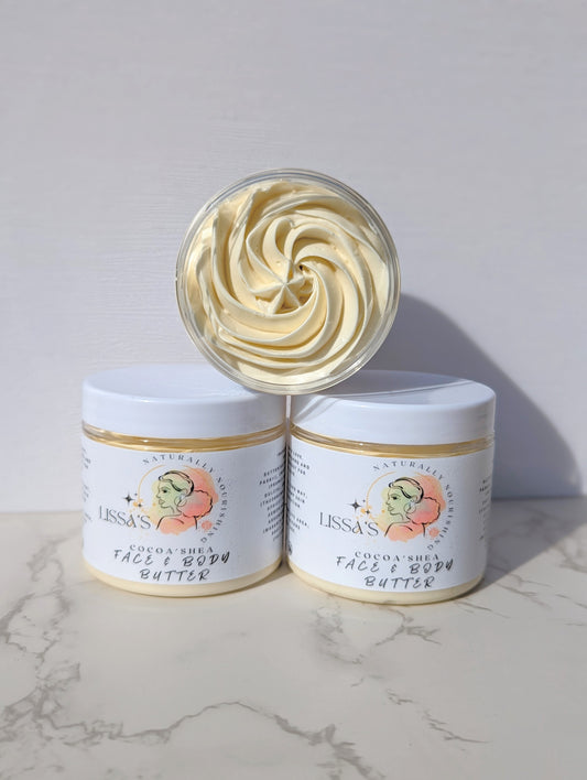 A jar of Cocoa'Shea Whipped Body Butter with the product visibly whipped into a creamy texture, displayed on a marble surface.